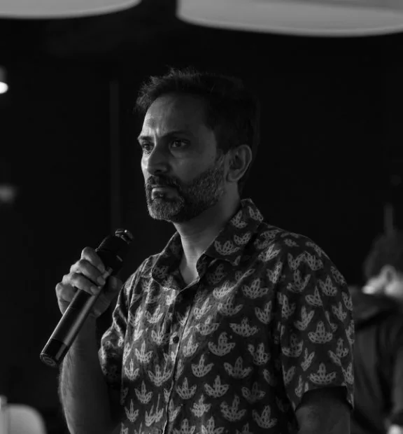 Brand consultant Sai Ganesh speaking into a microphone during his guest lecture, in black and white